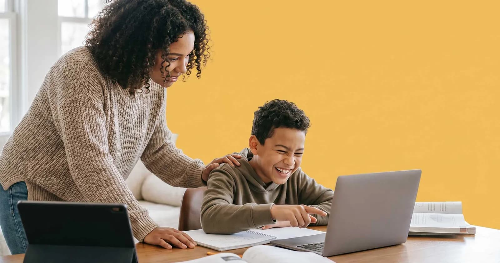 A adult assisting a young kid with a computer